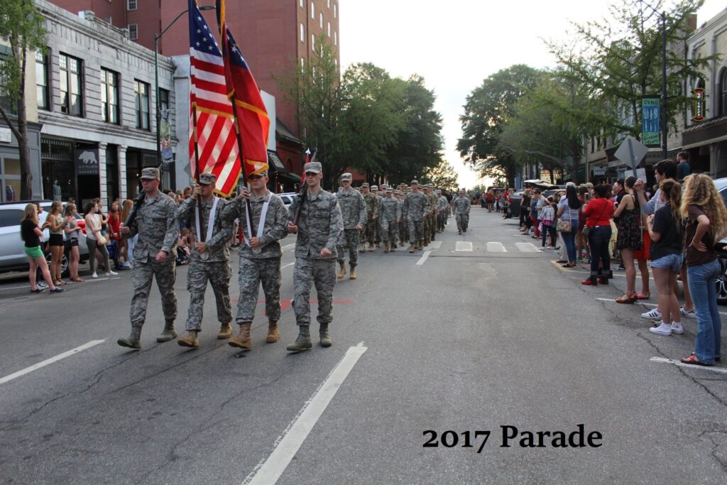 The 2017 Parade with four cadets walking in front in formation holding flags. 