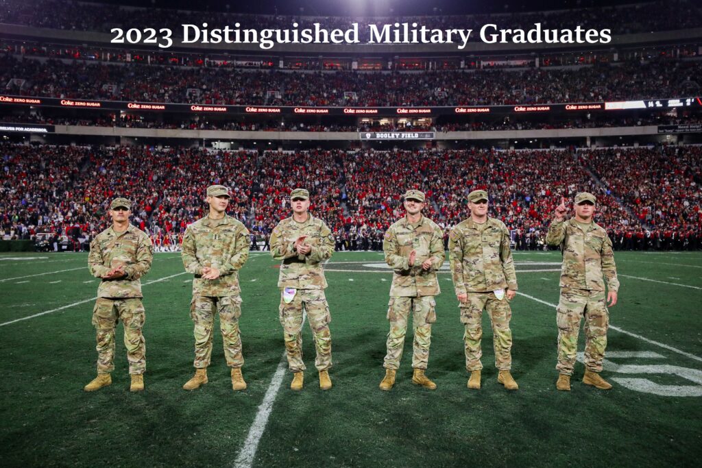 Six of the 2023 Distinguished Military Graduates on the field at Sanford Stadium in camouflage uniforms. 