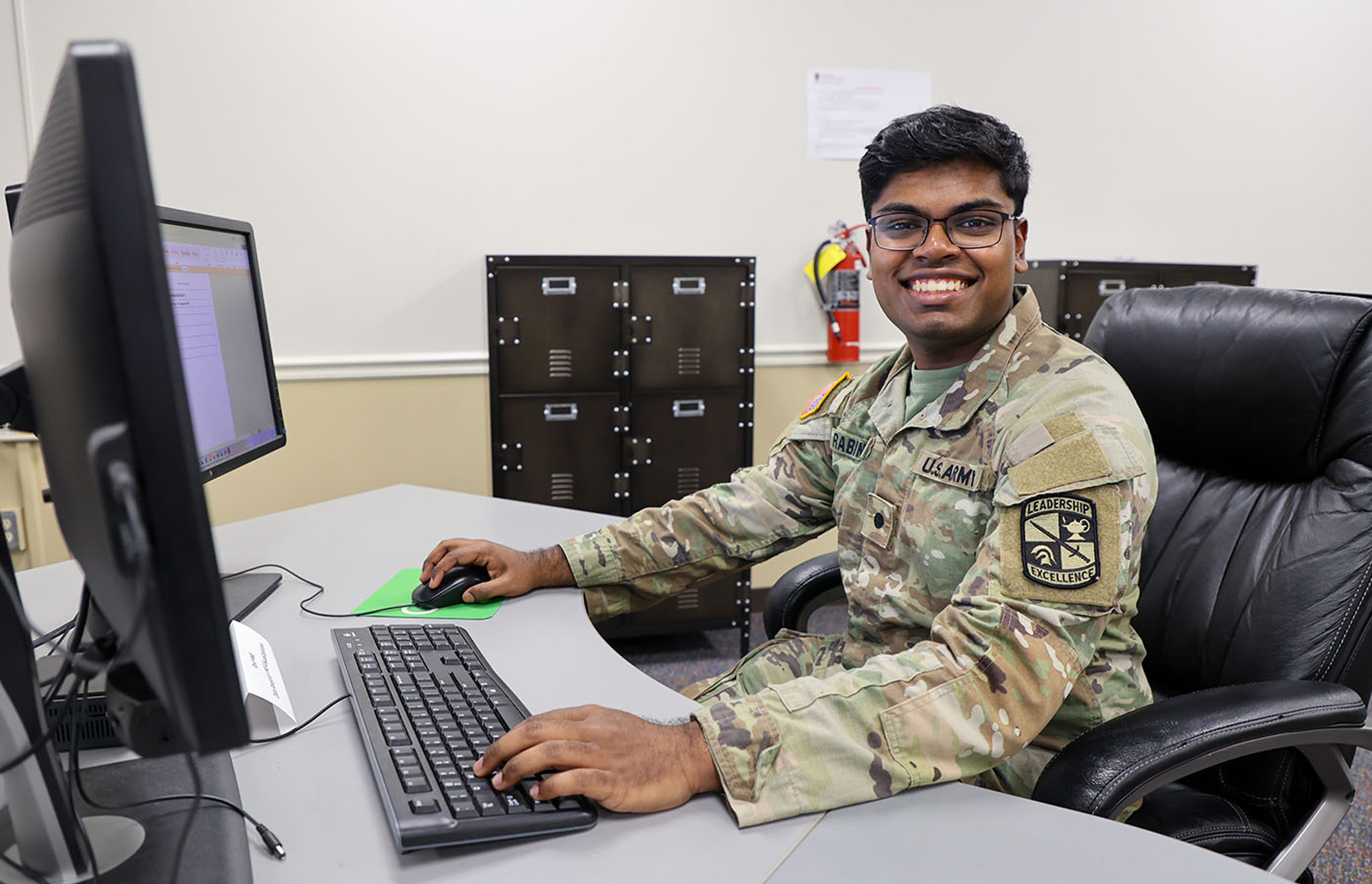 Richard Rabindran wears his UGA ROTC uniform while sitting at a computer with two screens.