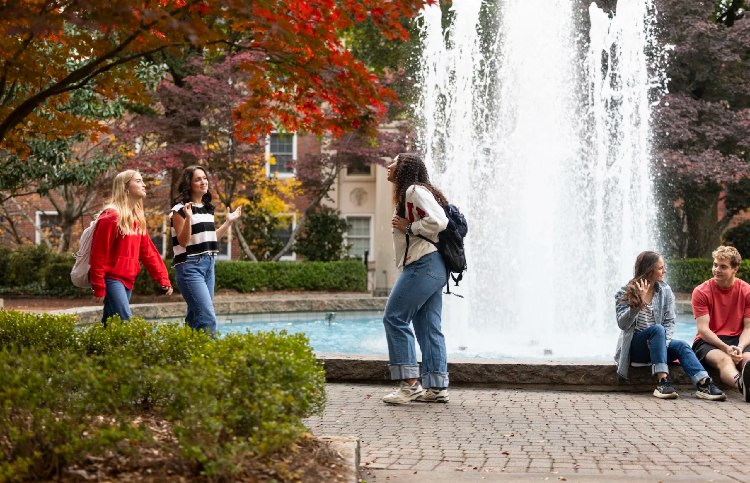 Image of the fountain during the fall with students walking by.